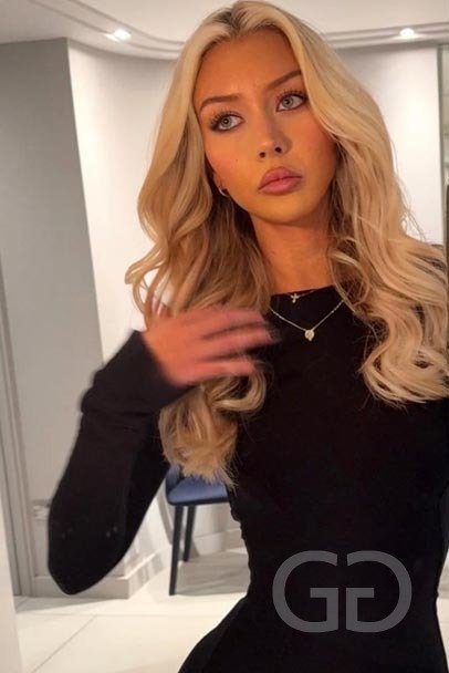 Talia - London escort in a black long-sleeved top, wavy blonde hair