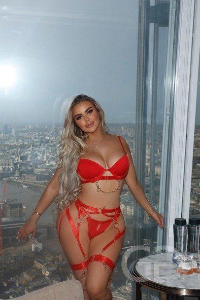 Scarlet in red strappy lingerie by a high window overlooking London