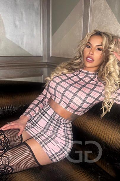Charlie with curly blonde hair in a pink check crop top and skirt