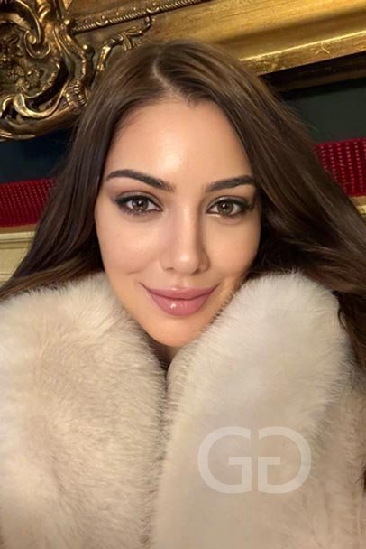 Eduarda, Brazilian escort in London, selfie in a cream fur coat with a gilt frame behind