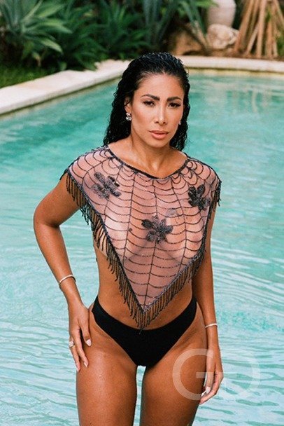 Nicole standing waist-deep in a pool in a black beaded top