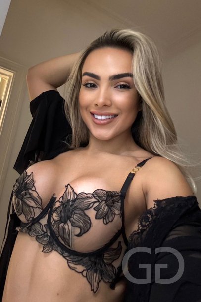 Karli - London escort in a black floral bra and sheer robe, smiling