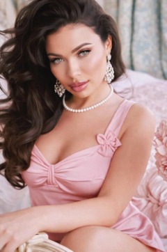 Sierra thumbnail in a pink dress with pearl necklace