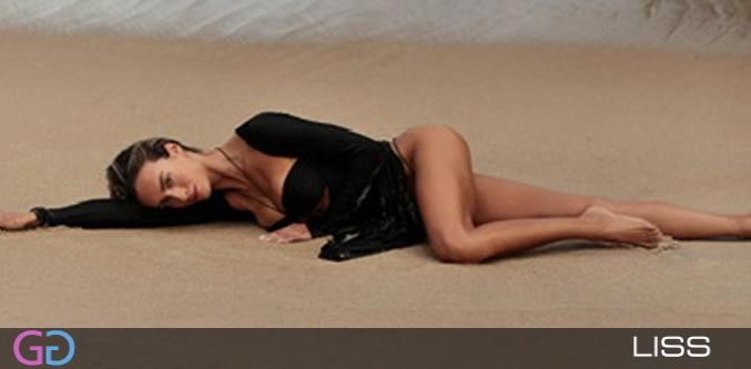 Brazilian high class escort Liss lying on the sand in a black top